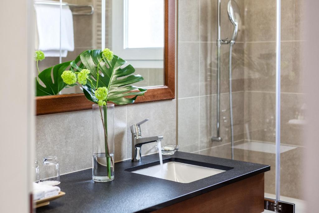 un bagno con lavandino e vaso con un fiore di Suitenhotel Parco Paradiso a Lugano