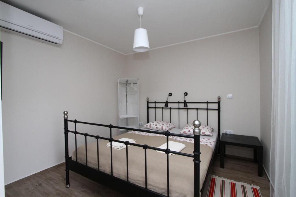 um quarto com uma cama preta num quarto branco em Ilona Apartmanház em Komárom