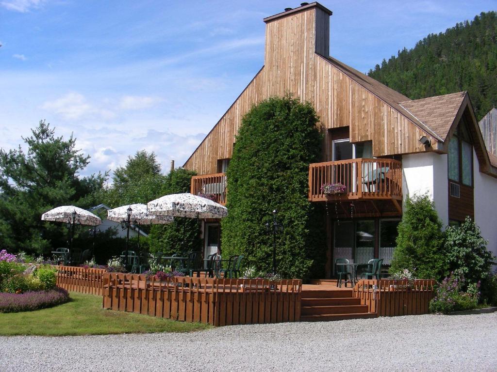 a building with a balcony and tables and chairs at Auberge du Jardin in Petit-Saguenay