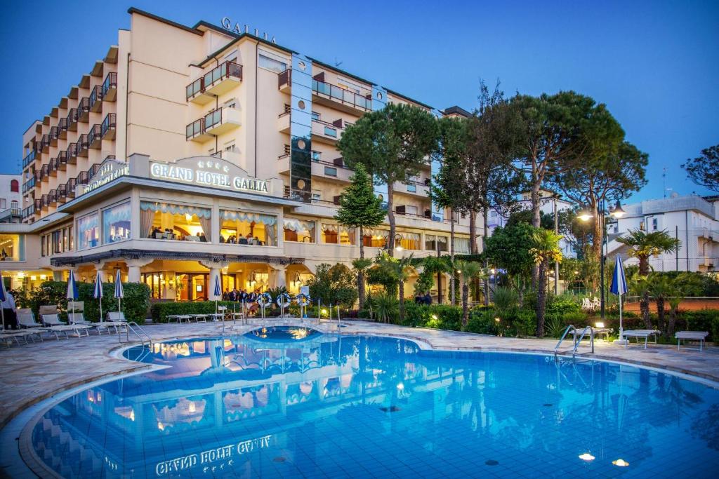 un hôtel avec une piscine en face d'un bâtiment dans l'établissement Grand Hotel Gallia, à Milano Marittima