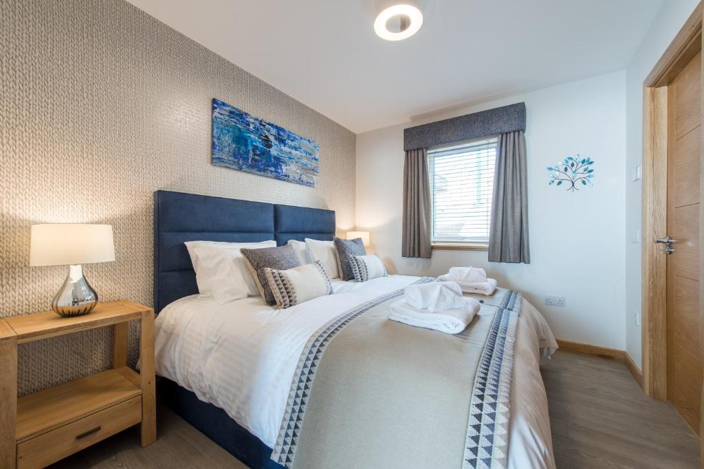 a bedroom with a large bed with a blue headboard at Dalriada Lodges Carlin in Stonehaven