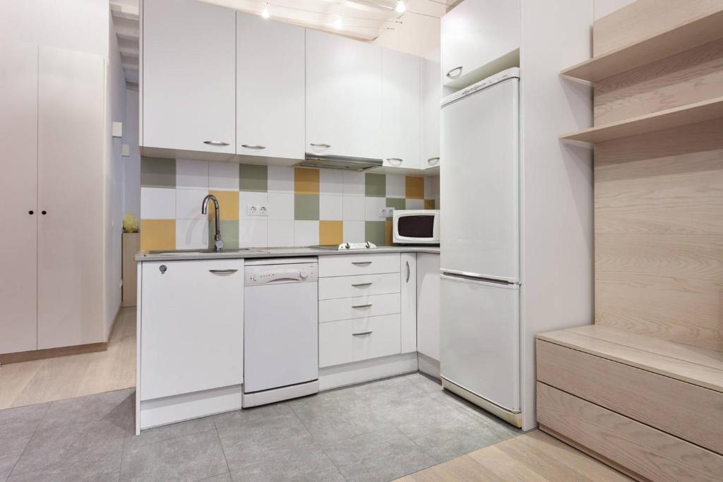 a kitchen with white cabinets and a white refrigerator at Nice apartment in Sants in Barcelona