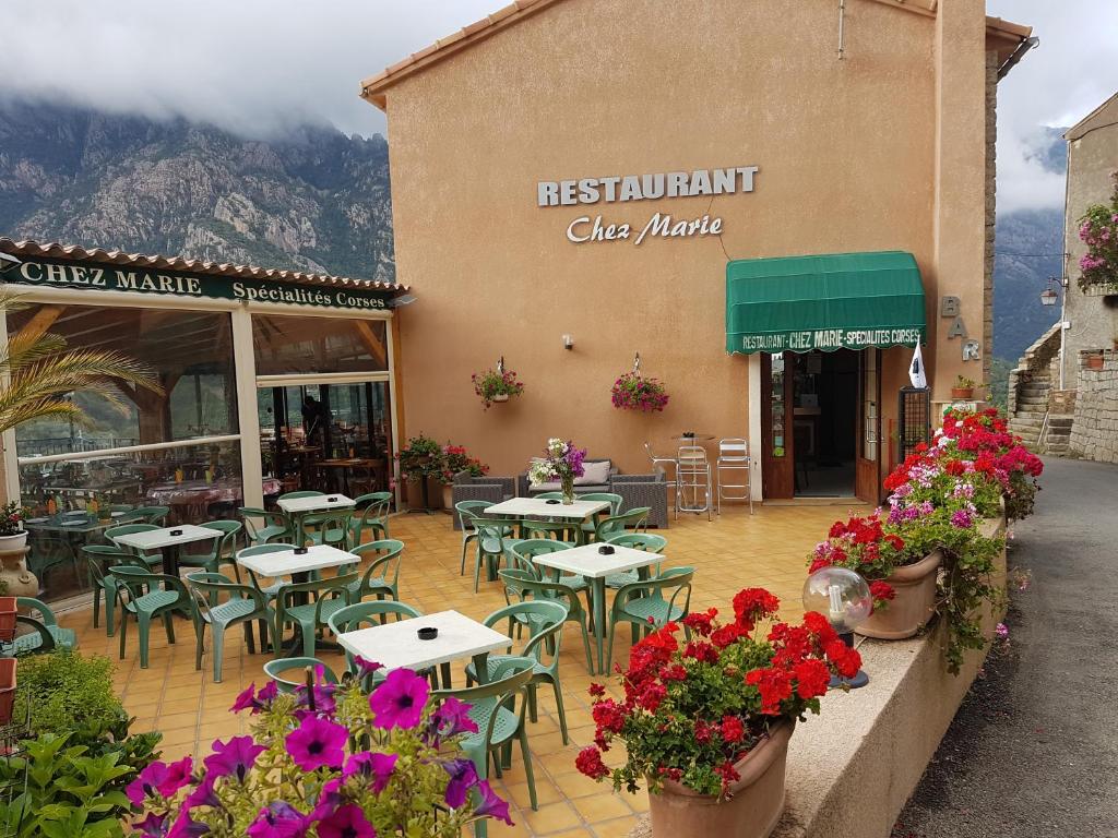 un restaurante con mesas, sillas y flores delante de él en chez marie, en Porto Ota