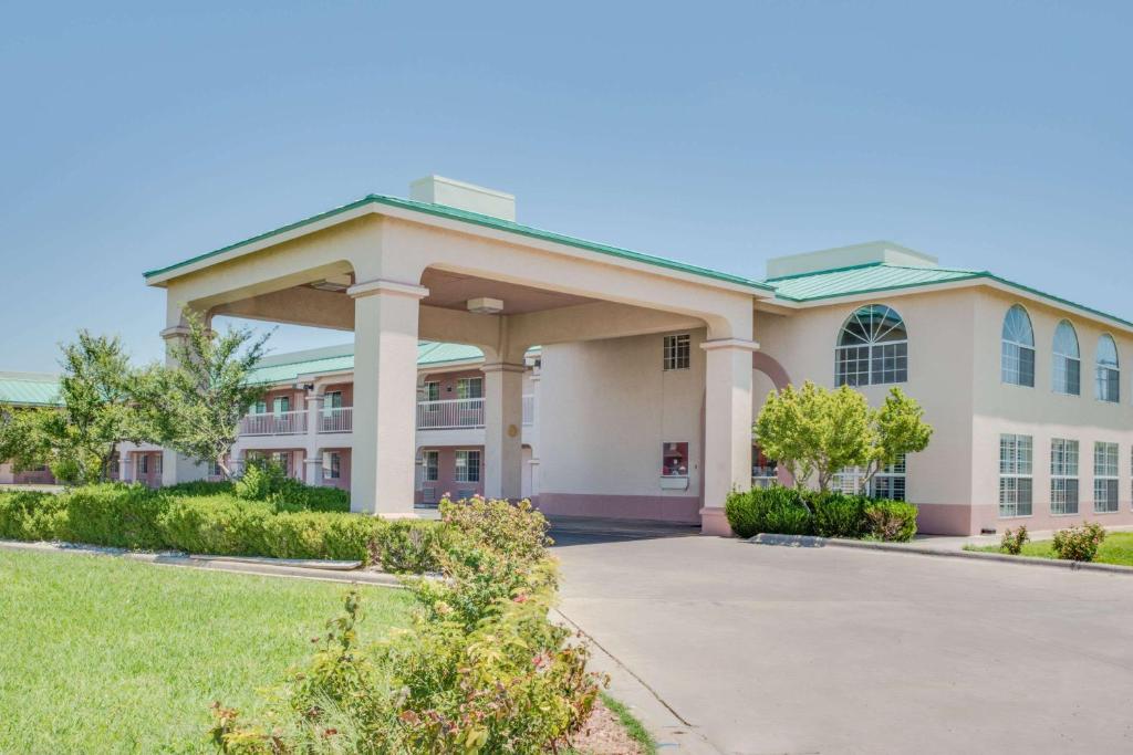 a large white building with a driveway at Days Inn by Wyndham Fort Stockton in Fort Stockton