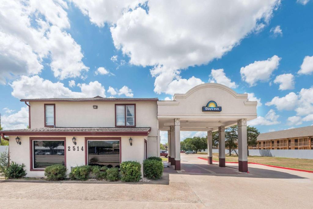 a building with a gas station in front of it at Days Inn by Wyndham Bryan College Station in College Station