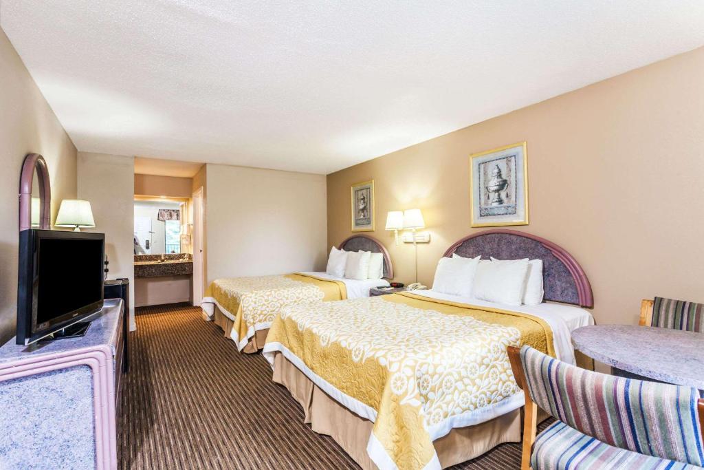 a hotel room with two beds and a flat screen tv at Days Inn by Wyndham Franklin Nashville in Franklin
