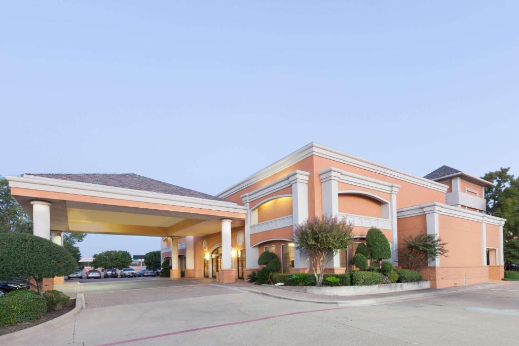 a hotel building with a parking lot at Days Inn by Wyndham Irving Grapevine DFW Airport North in Irving