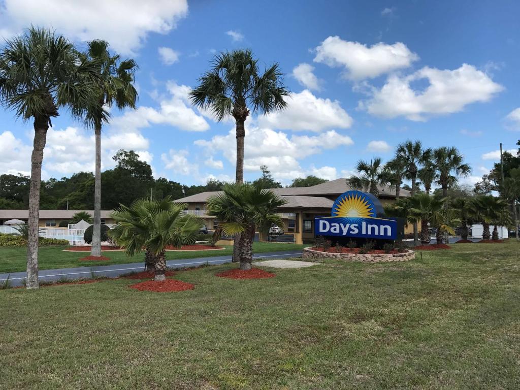 a day inn sign in front of a park with palm trees at Days Inn by Wyndham Orange City/Deland in Orange City