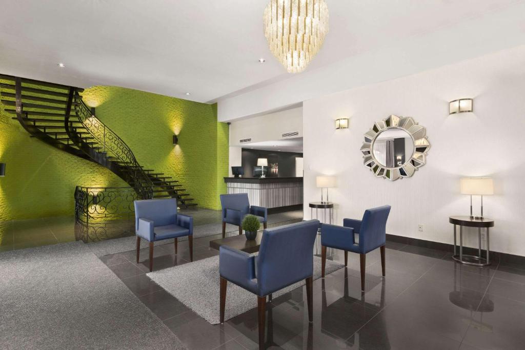 a lobby with blue chairs and a staircase at Days Inn by Wyndham Montreal Airport Conference Centre in Dorval