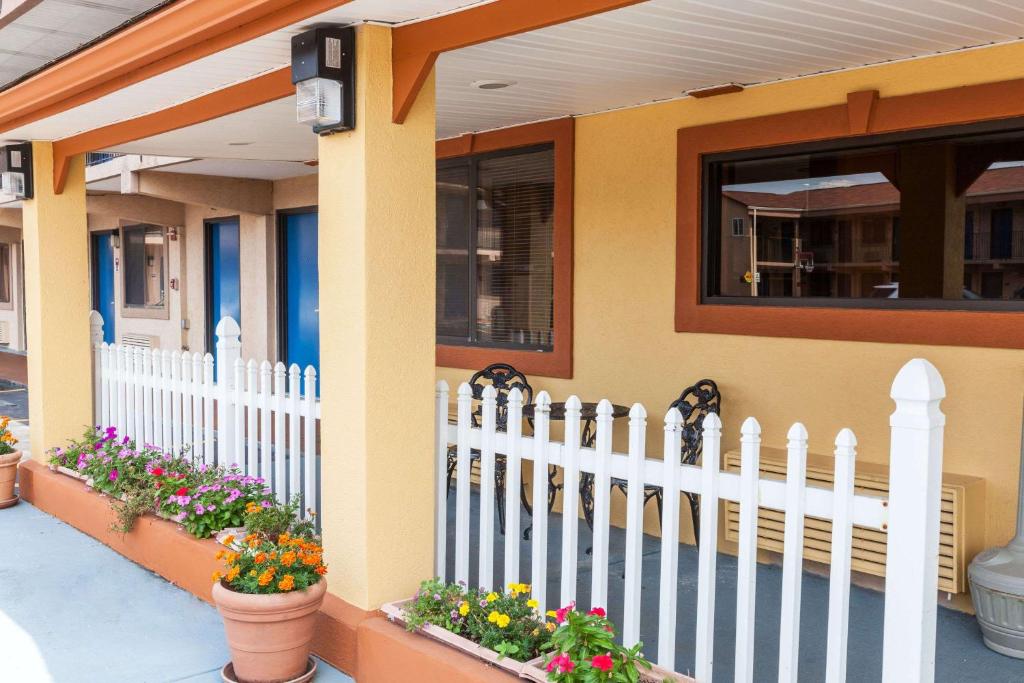 a white picket fence in front of a house with flowers at Red Carpet Inn Elkton in Elkton