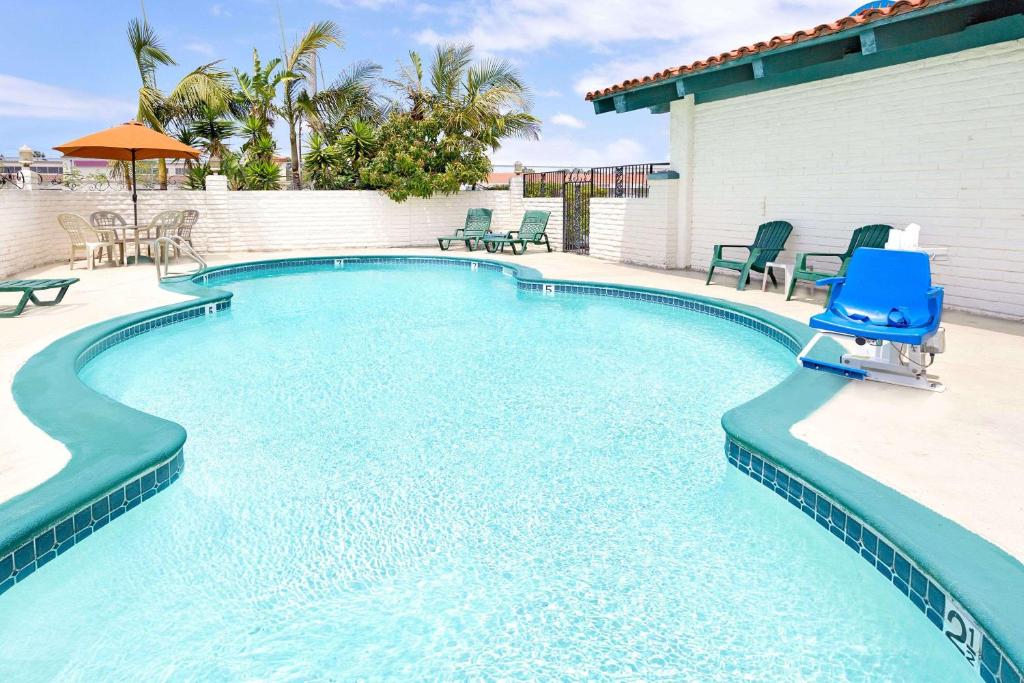 ein Pool mit einem blauen Stuhl in der Mitte in der Unterkunft Sunset Inn in Costa Mesa