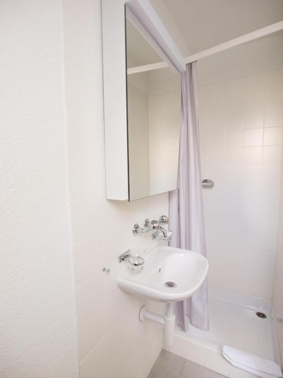 a white bathroom with a sink and a mirror at Hotel Gregory in Zürich