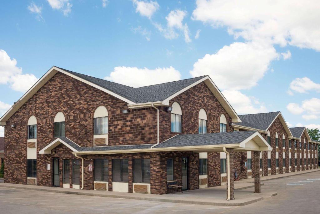 a large brick building with a black roof at Days Inn by Wyndham Muncie -Ball State University in Muncie