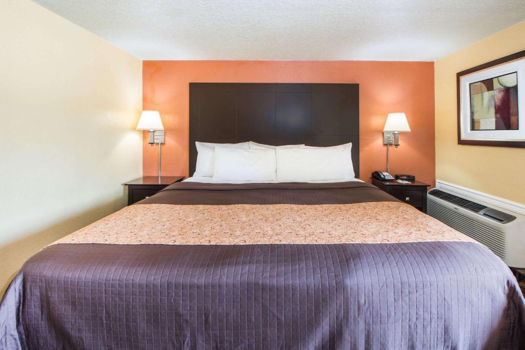 a large bed in a hotel room with two lamps at Days Inn by Wyndham Joplin in Joplin