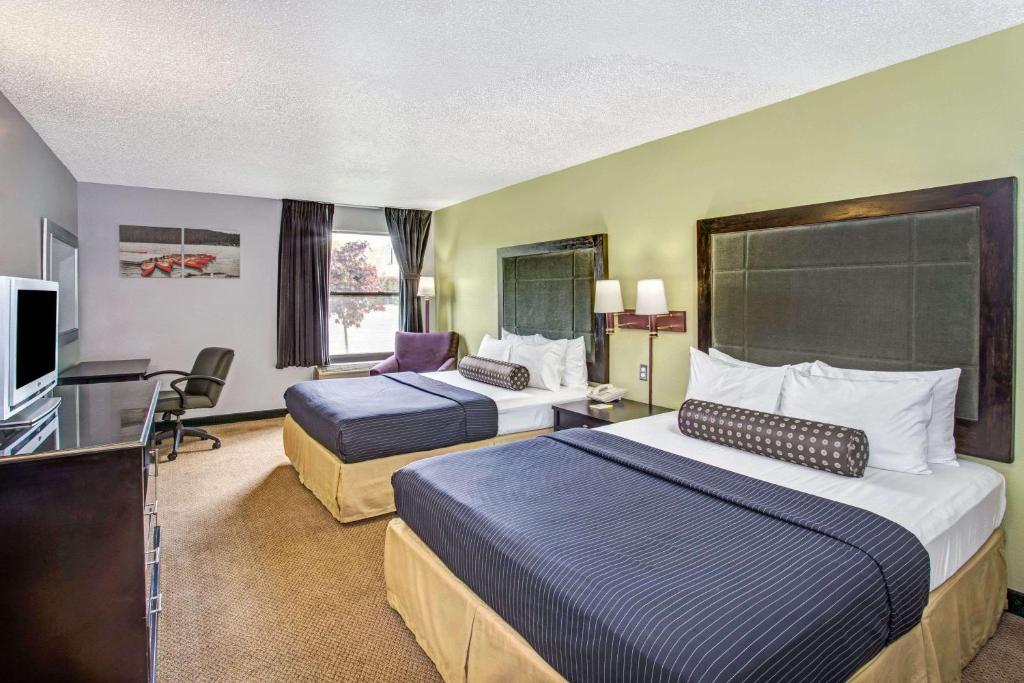 a hotel room with two beds and a television at Days Inn by Wyndham Great Lakes - N. Chicago in North Chicago