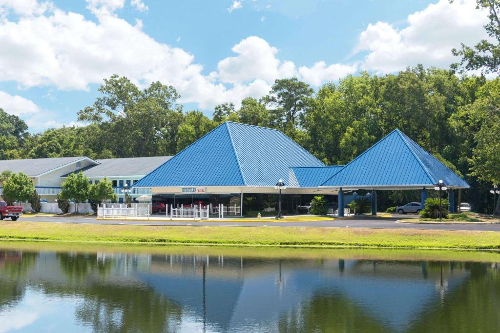 a building with a blue roof next to a lake at Days Inn by Wyndham Savannah Airport in Savannah