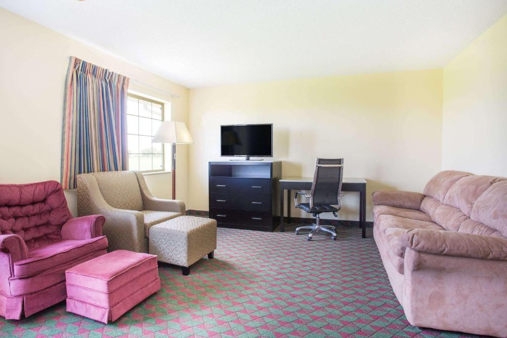 a hotel room with a couch and chairs and a desk at Days Inn by Wyndham Lexington NE in Lexington