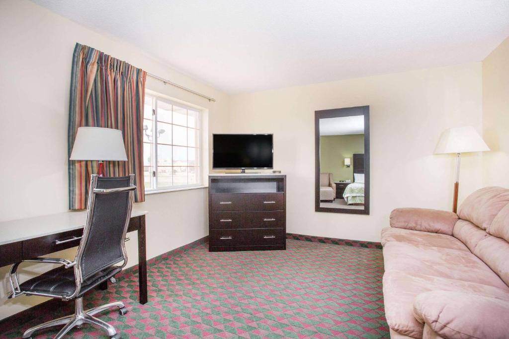 a hotel room with a couch and a desk and a television at Days Inn by Wyndham Lexington NE in Lexington