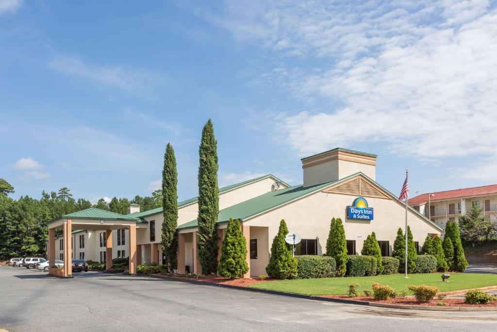 a front view of a hotel with trees at Days Inn & Suites by Wyndham Peachtree Corners Norcross in Norcross