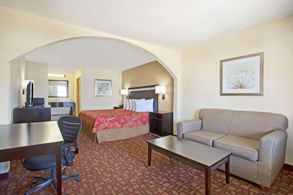 a hotel room with a bed and a couch and a desk at Days Inn by Wyndham Hammond in Hammond
