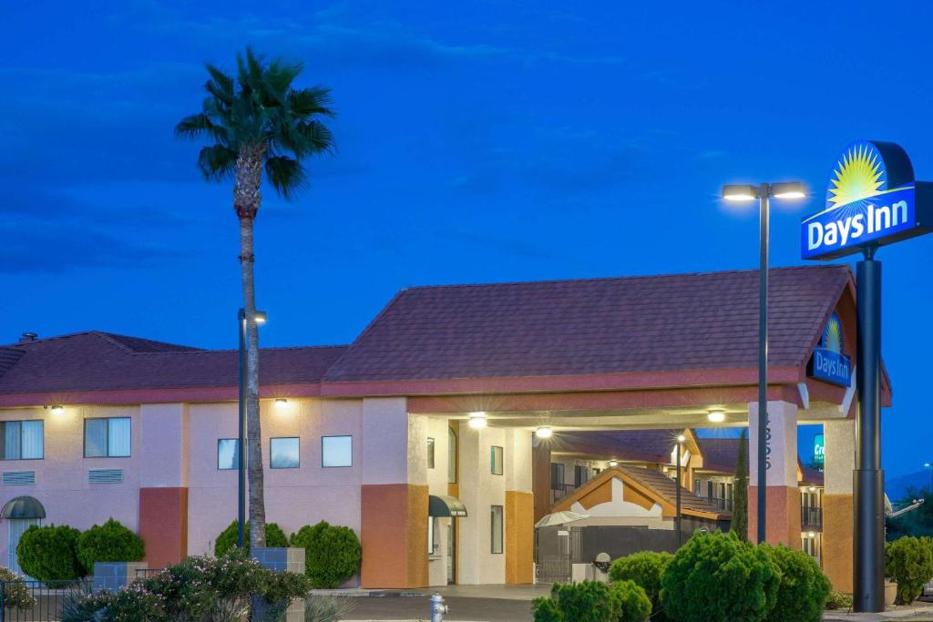 a hotel with a palm tree and a street sign at Days Inn by Wyndham Tucson Airport in Tucson