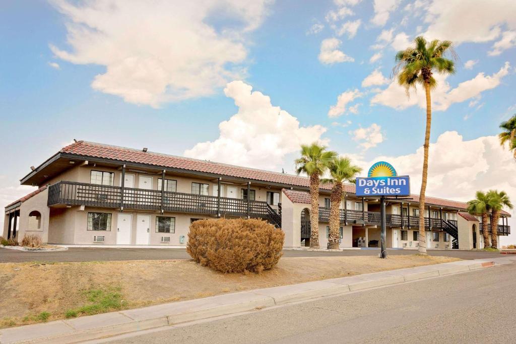 a dog inn with palm trees in front of it at Days Inn & Suites by Wyndham Needles in Needles