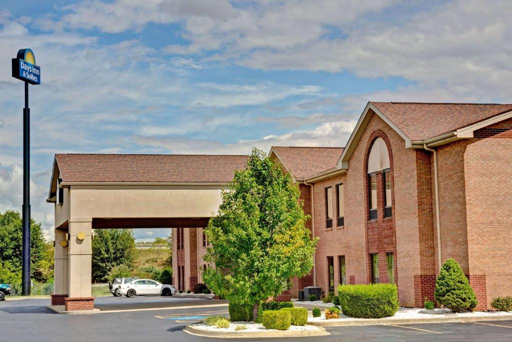 un gran edificio de ladrillo con un árbol en un aparcamiento en Days Inn & Suites by Wyndham Louisville SW en Louisville