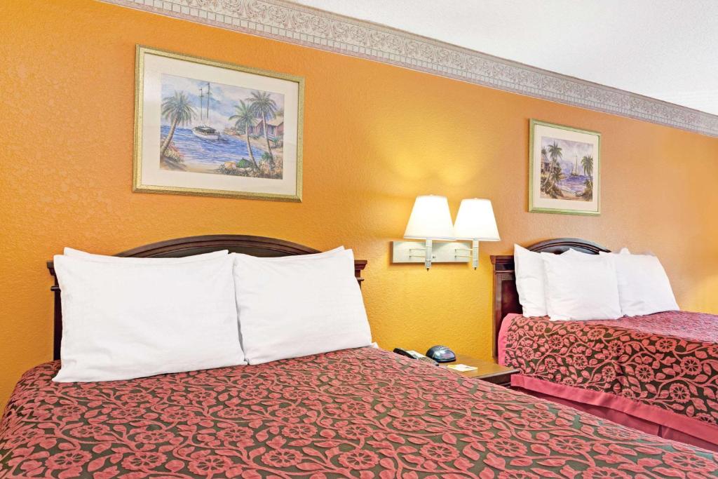 Sunset Inn Daytona Beach في دايتونا بيتش: غرفة فندقية بسريرين وجدران برتقالية