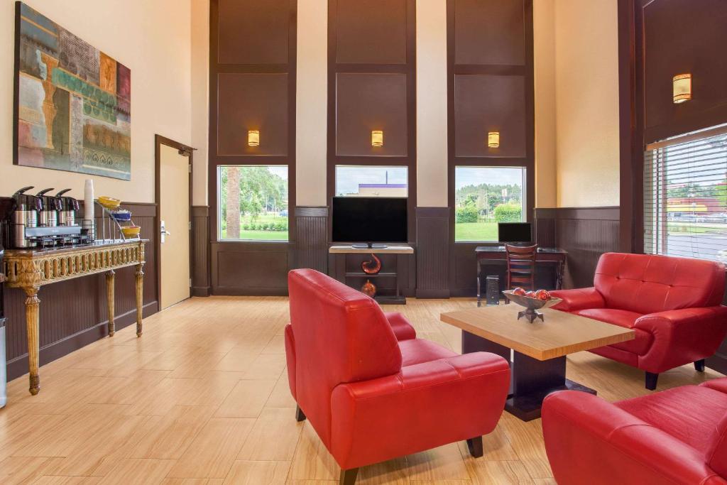 a living room with red chairs and a tv at Days Inn by Wyndham Brooksville in Brooksville