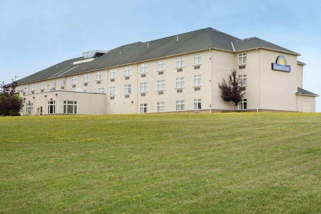 a large building with a large field in front of it at Days Inn by Wyndham Orillia in Orillia