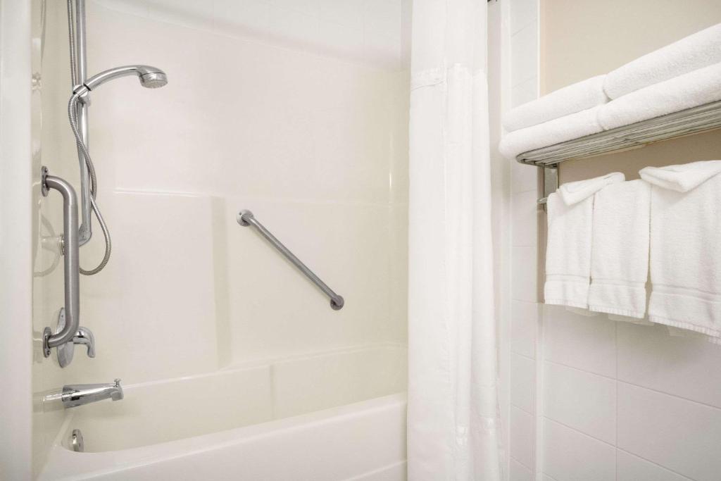 a white bathroom with a shower and a tub at Days Inn & Suites by Wyndham Langley in Langley
