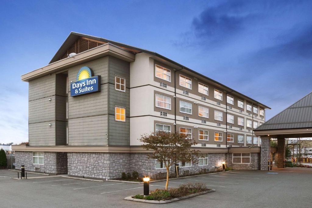 a front view of a hotel with a donut shop at Days Inn & Suites by Wyndham Langley in Langley