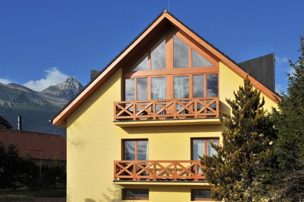 a yellow house with a balcony on top of it at APLEND Vila Magnolia in Tatranská Lomnica