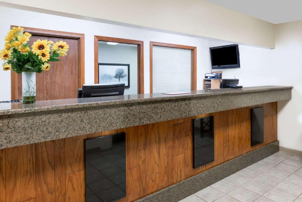 a lobby with a reception desk with a vase of flowers at Days Inn & Suites by Wyndham Des Moines Airport in Des Moines