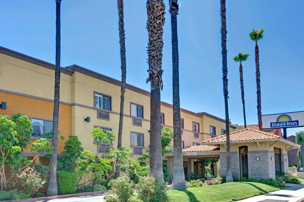 a row of palm trees in front of a building at Days Inn by Wyndham West Covina in West Covina