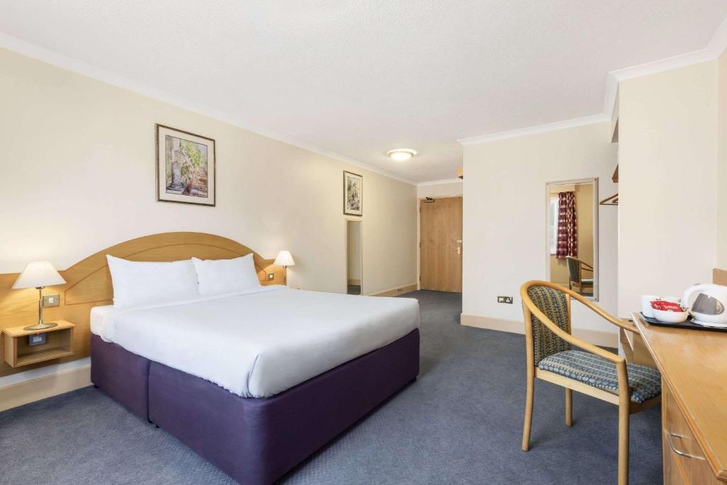 Habitación de hotel con cama grande y escritorio. en Days Inn Watford Gap en Crick