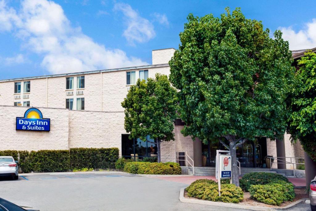 a building with a tree in front of it at Days Inn & Suites by Wyndham Fullerton in Fullerton