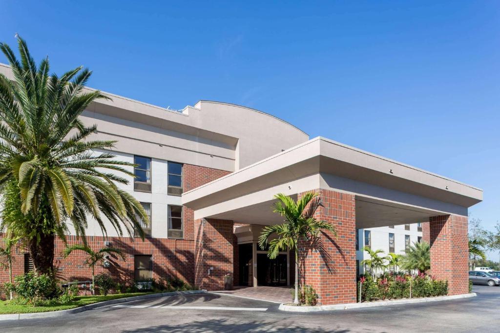 um edifício com uma palmeira em frente em Days Inn & Suites by Wyndham Fort Myers Near JetBlue Park em Fort Myers