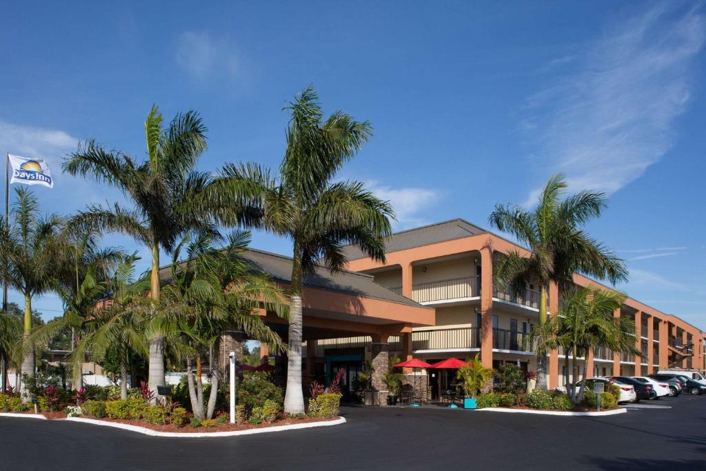 a hotel with palm trees in front of a parking lot at Days Inn by Wyndham Sarasota Bay in Sarasota