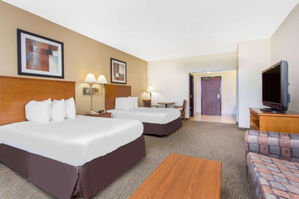 a hotel room with two beds and a flat screen tv at Days Inn By Wyndham Phenix City Near Fort Moore in Phenix City