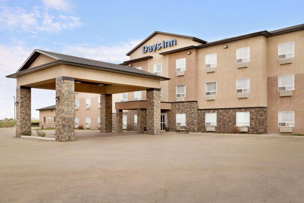 a hotel with a large parking lot in front of it at Days Inn by Wyndham Innisfail in Innisfail
