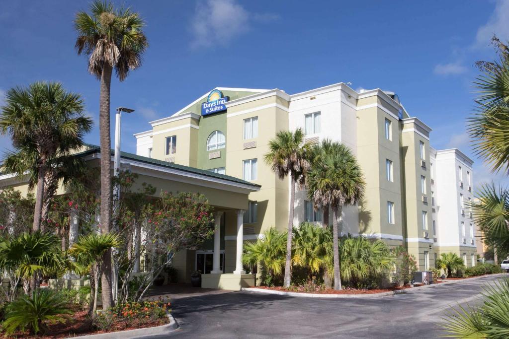 a hotel with palm trees in front of it at Days Inn & Suites by Wyndham Fort Pierce I-95 in Fort Pierce