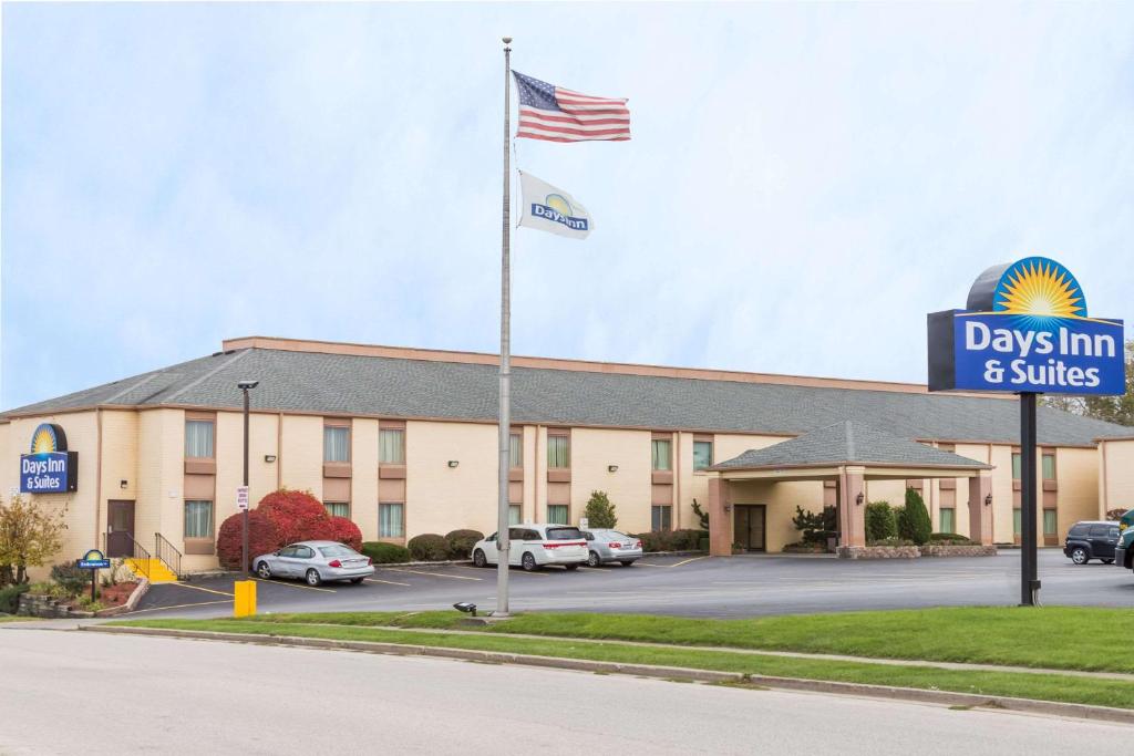 a view of a days inn and suites with an american flag at Days Inn & Suites by Wyndham Bloomington/Normal IL in Bloomington