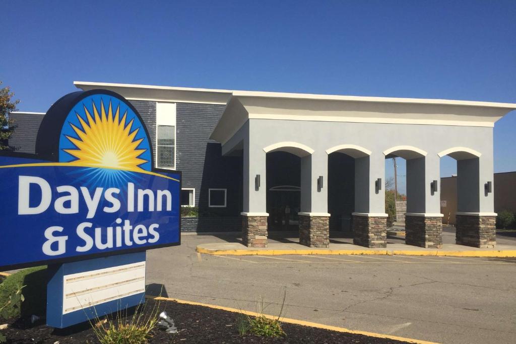 Un día de posada y suites firman frente a un edificio en Days Inn & Suites by Wyndham Cincinnati North en Springdale