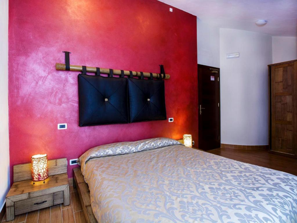 a bedroom with a bed and a red wall at Agriturismo Il Falco in Velletri