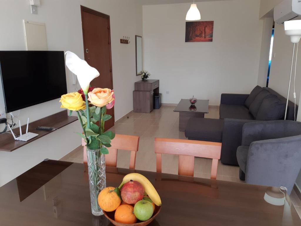 een woonkamer met een vaas met bloemen en fruit op een tafel bij Vasilas Holiday Apartment #1 in Larnaka