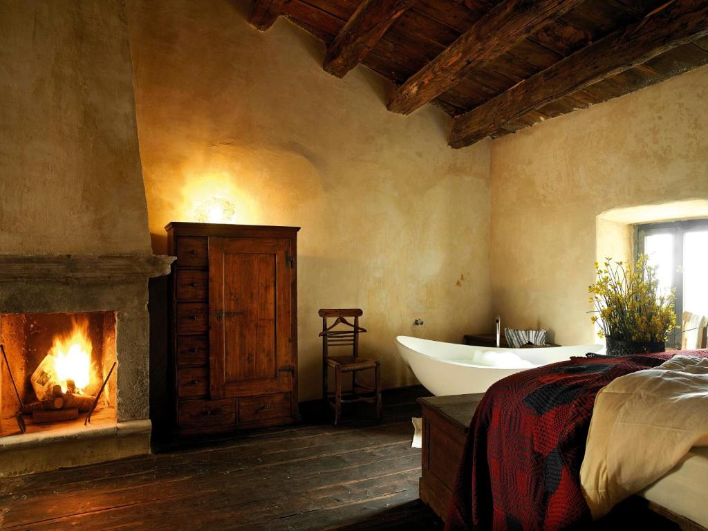 een slaapkamer met een bad en een open haard bij Sextantio Albergo Diffuso in Santo Stefano di Sessanio
