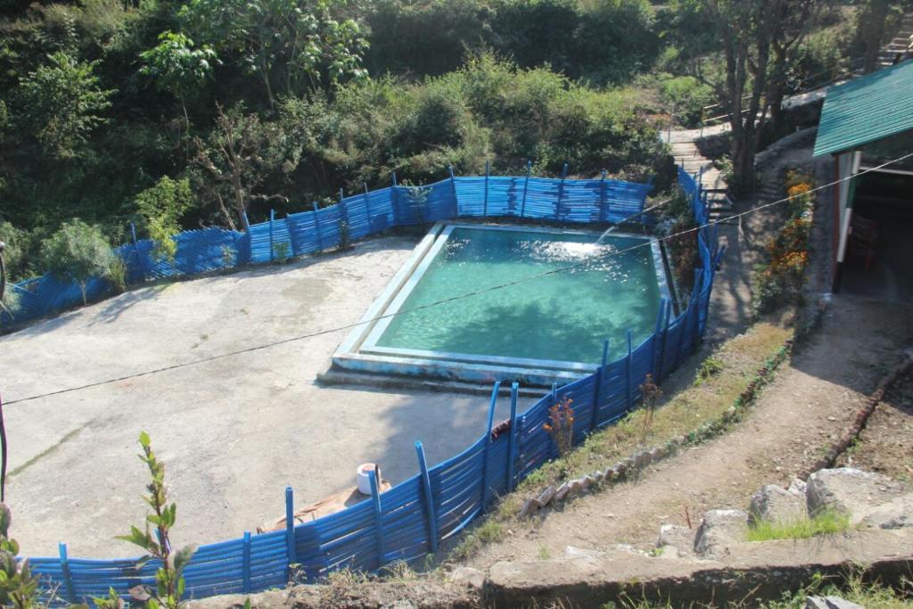 uma piscina com uma cerca azul à volta em Natural Camps with InHouse Swimming Pool em Rishikesh