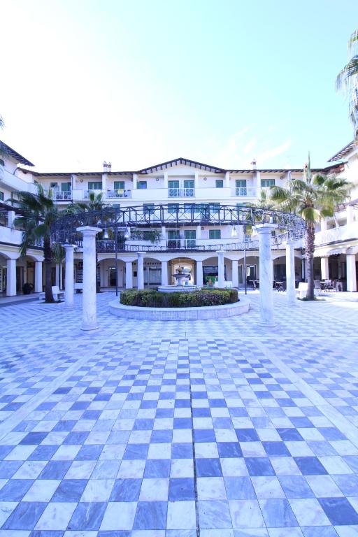 a large white building with a courtyard with palm trees at CYTRUS apartament in Marina di Massa