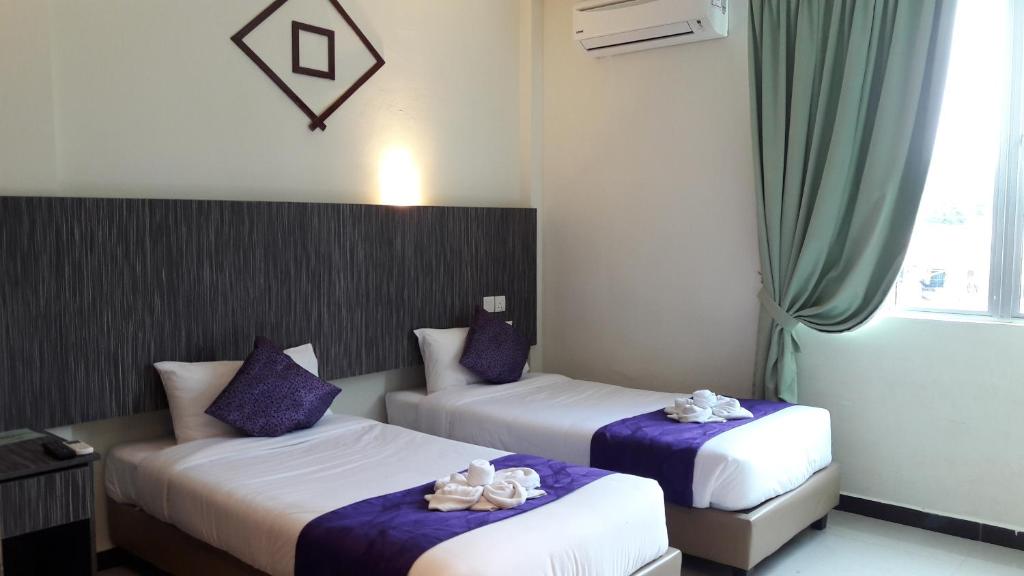 two beds in a hotel room with shoes on them at Salsa Resort Langkawi By Casa Loma in Pantai Cenang
